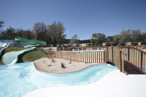 un toboggan dans un parc avec une clôture en bois dans l'établissement Mobil home Bord de Mer, à Fouesnant