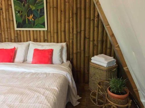 a bedroom with a bed with red pillows and a plant at Balili Garden at Nacpan in El Nido