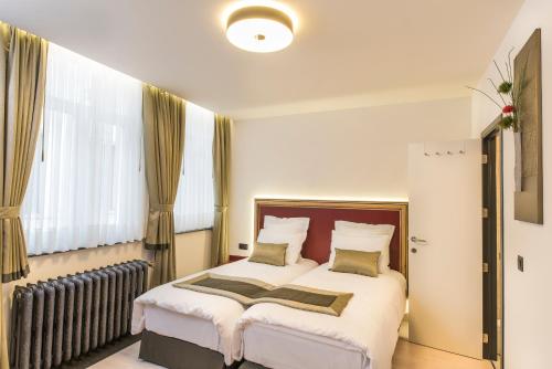 a bedroom with a white bedspread and white curtains at Hotel Agora Brussels Grand Place in Brussels