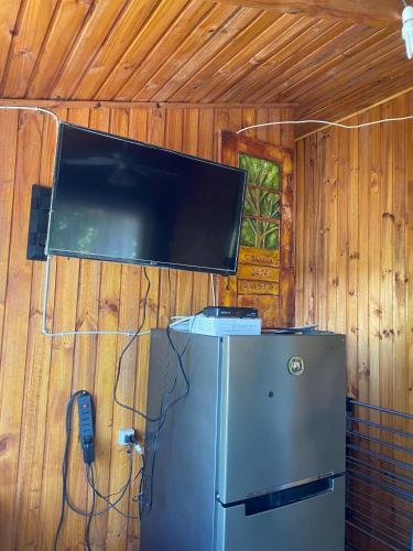 einen TV an einer Wand mit einem Kühlschrank und einem Telefon in der Unterkunft Cabaña en Quinchamalí in Quinchamali