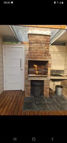 a brick fireplace in a backyard with a white door at Casa De Madeira á beira mar Ponta Malongane in Maputo