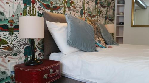 a bed with pillows and a lamp on a red trunk at Peterborough House in Saint Aubin