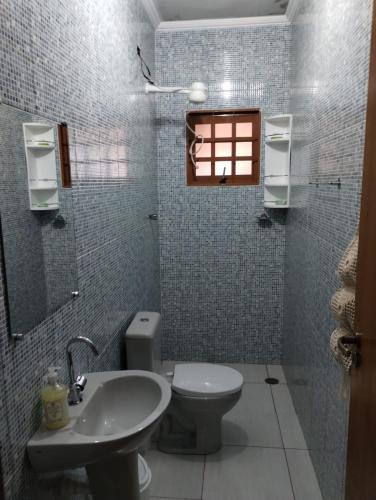 a bathroom with a toilet and a sink and a window at Recanto da Família in Quadra