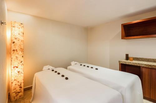 two beds in a room with white sheets at Fiesta Americana Acapulco Villas in Acapulco