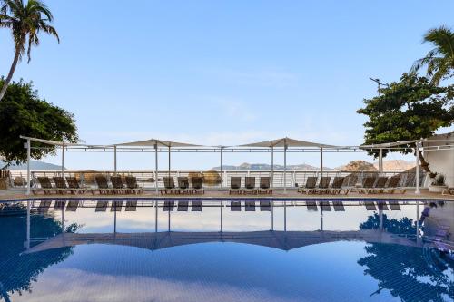 a swimming pool with chairs and umbrellas in a resort at Fiesta Americana Acapulco Villas in Acapulco