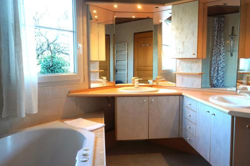 a bathroom with a tub and two sinks and a mirror at Gite MontBlanc in Verrens-Arvey