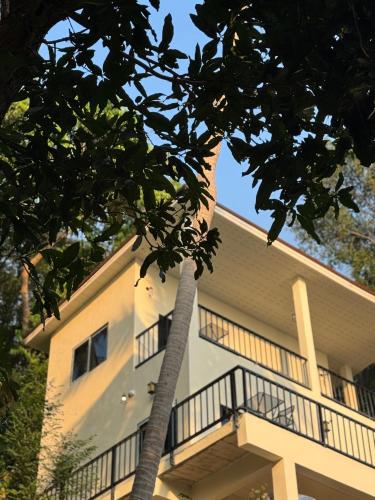 a building with a palm tree in front of it at Tanouy Garden in Baan Khai