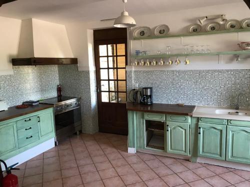 une cuisine avec des armoires vertes et une cuisinière four supérieur dans l'établissement la ferme, Coeur De Combray, à Ernes