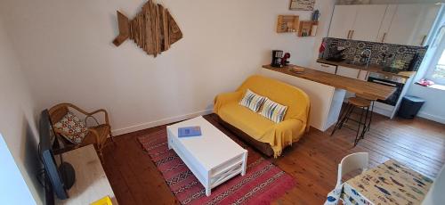 Una sala de estar con un sofá amarillo y una mesa. en Le Gîte de l'Amer - T2 - Duplex - Centre Bourg, en Baden