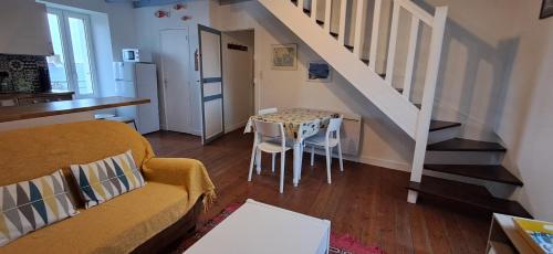 sala de estar con sofá, mesa y escalera en Le Gîte de l'Amer - T2 - Duplex - Centre Bourg, en Baden