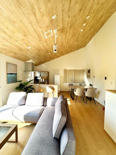 a living room with a couch and a wooden ceiling at Hoco 富士急ハイランド in Funatsu