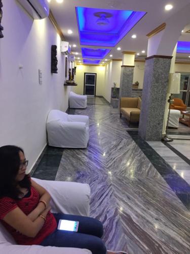 a woman sitting on a couch in a waiting room at Gautama Hotel in Khajurāho