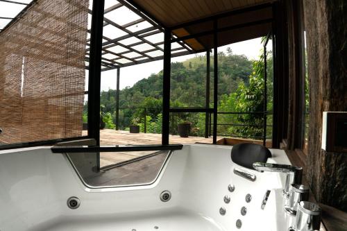 a bathroom with a tub with a view of the forest at Arana Sri Lanka Eco Lodge and Yoga Center in Ella