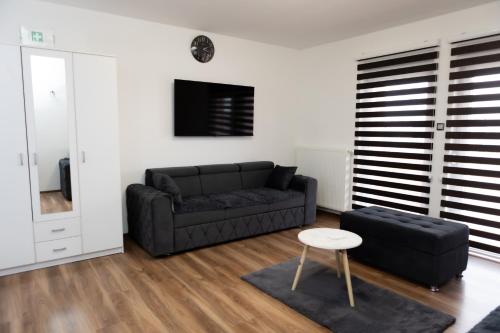 a living room with a black couch and a stool at Apartmani Leila in Gospić