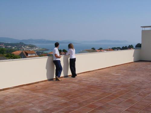 a man and woman standing on top of a white wall at Hotel Oca Vermar in Aios