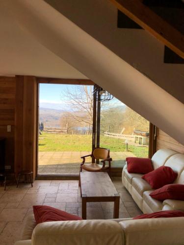 - un salon avec des canapés et une grande fenêtre dans l'établissement Gite La Grange sur les Bois, à Aiguebelette-le-Lac