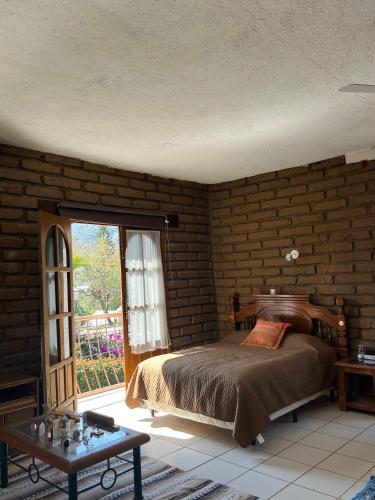 ein Schlafzimmer mit einem Bett und einer Ziegelwand in der Unterkunft Casa de los ángeles en el centro in Malinalco