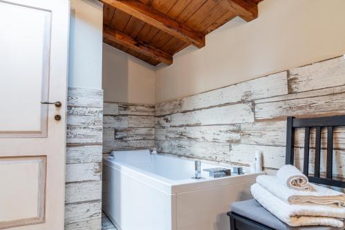 a bathroom with a white tub and wooden wall at Villa Lux Poggelleri vista unica sul Casentino in Poppi