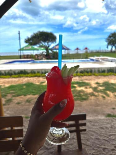 a hand holding a red drink with a blue straw at Playa Aescondidas in Ríohacha