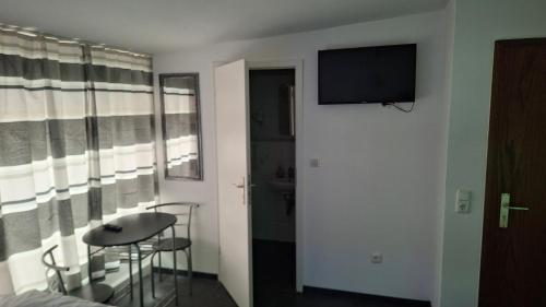 a room with a table and a television on a wall at Pension Alis Augsburg in Augsburg