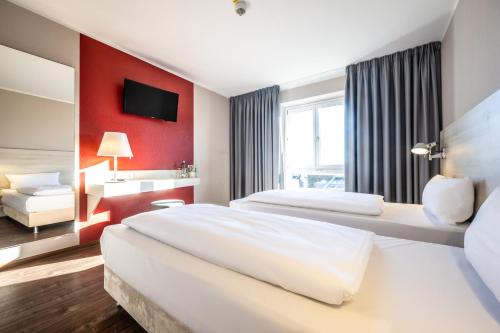 a hotel room with two beds and a red wall at Hotel Irschenberg Süd in Irschenberg