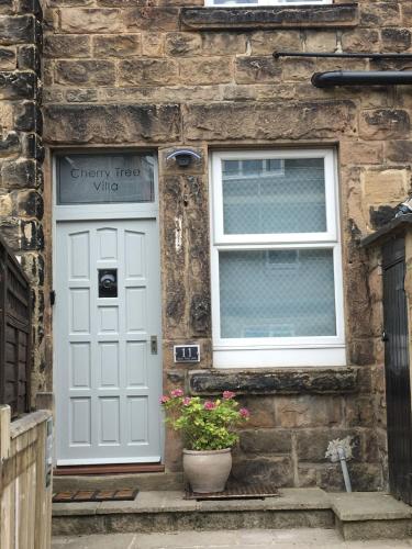 a stone house with white doors and a potted plant at Cherry Tree Villa in Harrogate