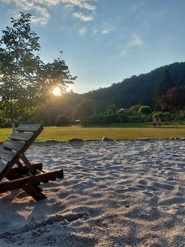 a wooden bench sitting in a field with the sun in the background at Ciucea185 -Casa din Livadă in Ciucea