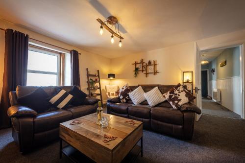 a living room with leather couches and a coffee table at 9A Bayfield Road in Portree
