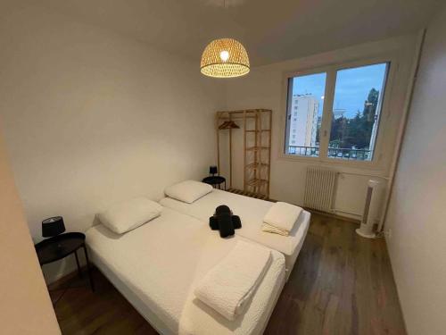 Cette chambre comprend un lit avec des draps blancs et une grande fenêtre. dans l'établissement Agréable logement 8 personnes, à Chalon-sur-Saône