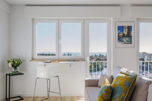 a living room with three windows and a couch at Sunset Horizon Carcavelos in Carcavelos