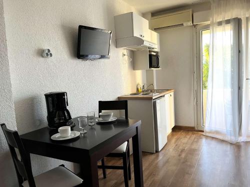 une cuisine avec une table et des chaises et une cuisine avec une télévision dans l'établissement SAINT-FLORENT Résidence piscine Studio 2 personnes FLO130, à Saint-Florent