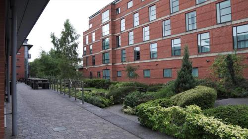 a brick building with a garden in front of a building at Broad Gauge Apartments in Wolverhampton