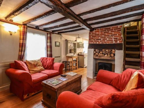 a living room with red furniture and a fireplace at Driftwood Cottage in Harwich