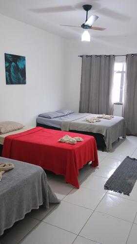 Cette chambre comprend 2 lits et une couverture rouge. dans l'établissement Apartamento Brisa 201, à Pedra de Guaratiba
