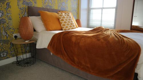 a bedroom with a bed with an orange blanket on it at Peterborough House in Saint Aubin