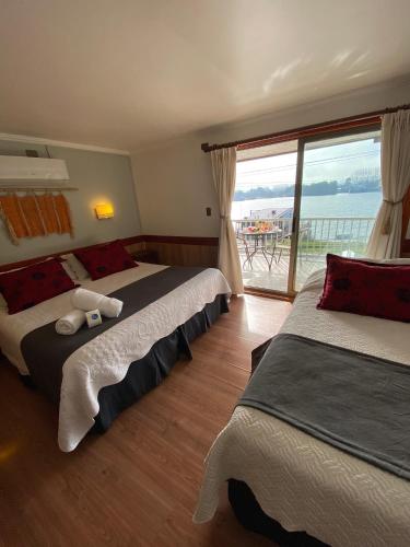 two beds in a room with a view of the ocean at Hotel Encanto del Río in Valdivia