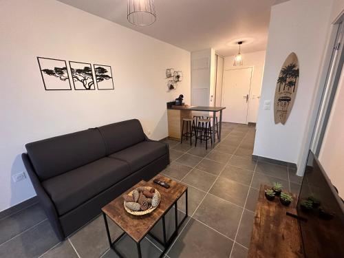 un salon avec un canapé noir et une table dans l'établissement À 500m de la plage - L Ébène -, à Mimizan-Plage