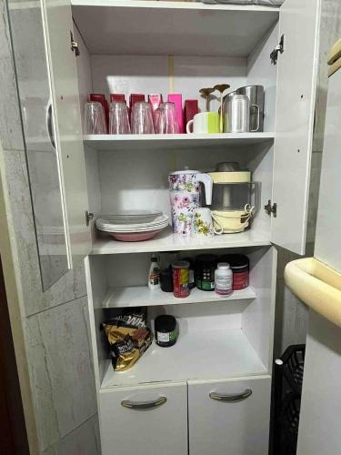 a white cupboard with dishes and utensils at Sobrado na Praia de Matinhos in Matinhos