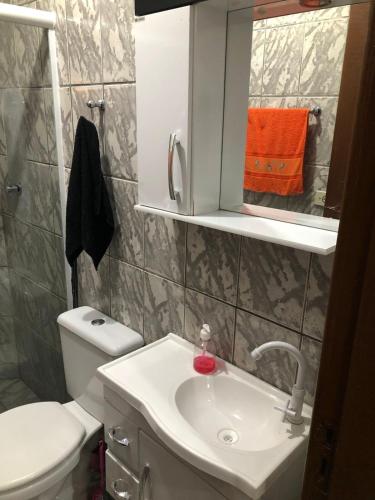 a bathroom with a sink and a toilet and a mirror at Sobrado na Praia de Matinhos in Matinhos