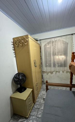 a room with a bed and a cabinet and a window at Sobrado na Praia de Matinhos in Matinhos