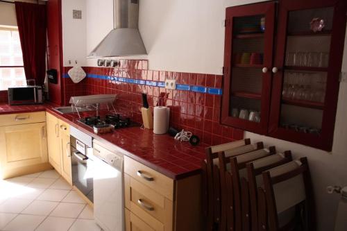 - une cuisine avec des murs carrelés rouges et un comptoir rouge dans l'établissement Moulines 10 bis, à Lansargues