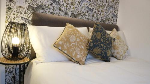a bedroom with a bed with pillows and a lamp at Peterborough House in Saint Aubin