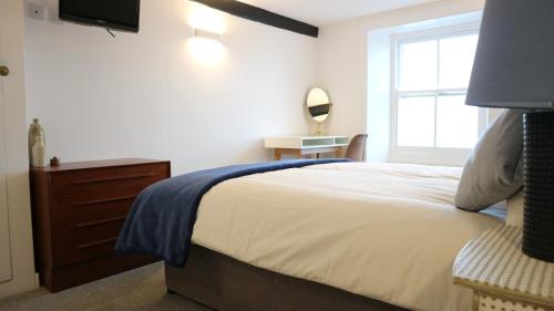 a bedroom with a bed with a dresser and a window at Peterborough House in Saint Aubin