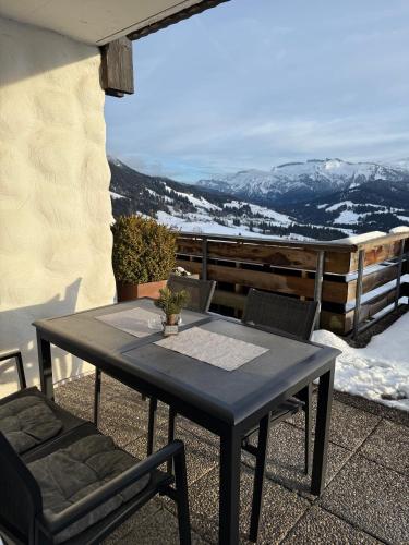 a table and chairs on a patio with snow covered mountains at Ferienwohnung & Spa Renate in Sibratsgfäll