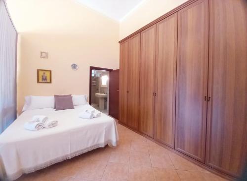 a bedroom with a white bed and wooden cabinets at Casa delle Tholos in Raccuia