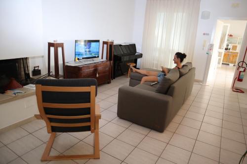 a man sitting on a couch watching a television at B&B LA CASA DEL CASALE in Roseto degli Abruzzi