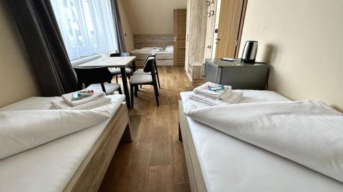 two beds in a room with a table and chairs at Ubytování U Pupka in Vrbovec