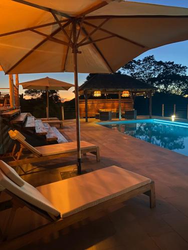 un patio con sedie e ombrelloni accanto a una piscina di VILLA JONGOA a Nosy Be