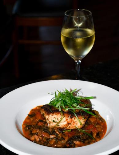 a white plate of food with a glass of wine at Francis Marion Hotel in Charleston