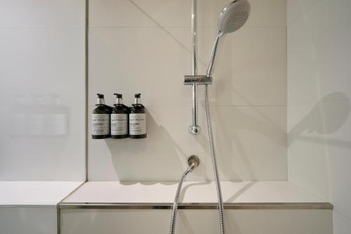 a shower with three bottles on a shelf at Catalonia El Retiro in Madrid